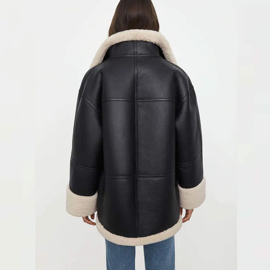 Back view of a women’s oversized black shearling jacket made from goatskin leather with faux fur lining. The oversized cut drapes naturally, with cream shearling accents along the hem, collar, and cuffs. This relaxed-fit shearling coat is designed for warmth and style, making it an essential oversized winter leather jacket for women who value comfort and timeless fashion.