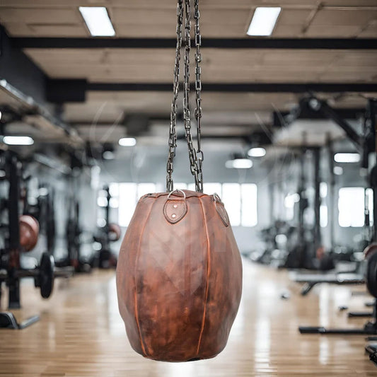 Side profile of the Brutestone Leather Wrecking Ball Punching Bag suspended by a heavy-duty steel chain. Its rugged cowhide exterior, reinforced stitching, and vintage finish offer durability and elegance. Ideal for uppercut and hook drills in boxing, martial arts, and combat fitness routines at home or in professional gyms.