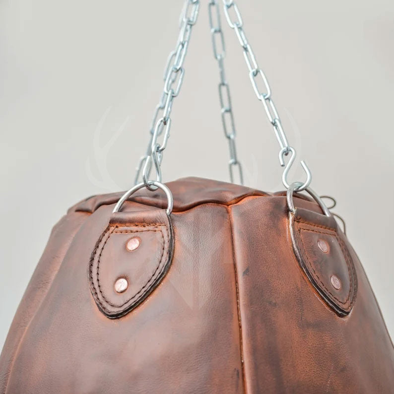 Angled view of the vintage-style Brutestone Punching Bag showing its full-grain leather construction, round wrecking ball shape, and sturdy chain mount. This bag is perfect for intensive boxing and MMA training, offering pro-level impact absorption, compact design, and a retro aesthetic fit for both home and commercial gym decor.