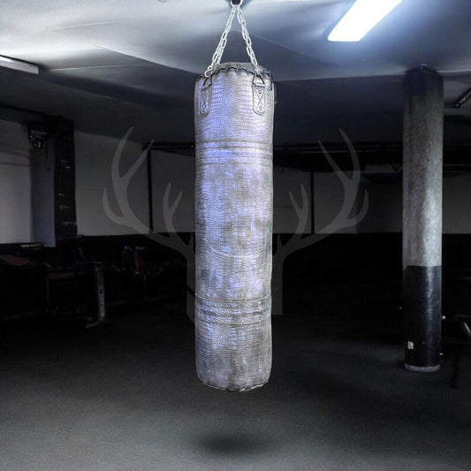 The Azure Mauler Crocodile Leather Punching Bag in blue showcases a unique crocodile-embossed cowhide exterior, offering a premium look and long-lasting performance. Ideal for boxing, MMA, and kickboxing training, this bag combines artisan craftsmanship with durable construction and is perfect for stylish home gyms and studios.