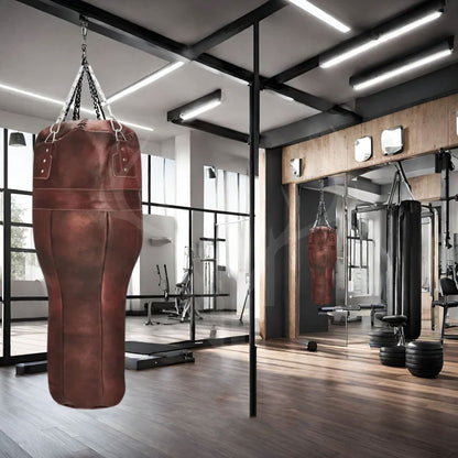 A wide-angle gym view with the Ironclad Titan Uppercut Boxing Bag suspended, surrounded by boxing gloves and training equipment. The bag’s robust leather and angled design support precise uppercut strikes, enhancing fighter agility and technique.

