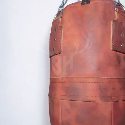 Extreme close-up showing the rugged cowhide leather texture and meticulous hand-stitched seams of the Striker Uppercut punching bag, under soft lighting that reveals the bag’s vintage aesthetic and durability, crafted for intense combat sports training.

